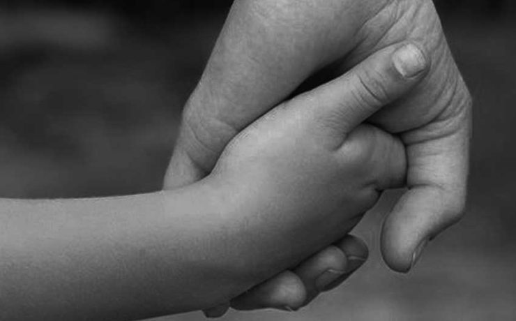 Woman holding a child's hand just like a মা