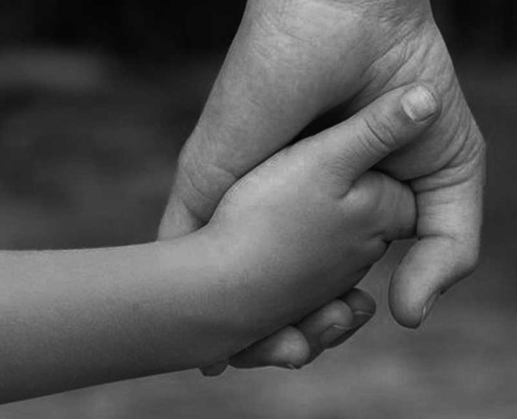 Woman holding a child's hand just like a মা