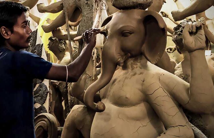 An artisan applies finishing touches to a clay idol of Ganesha at a workshop in Delhi, India.
