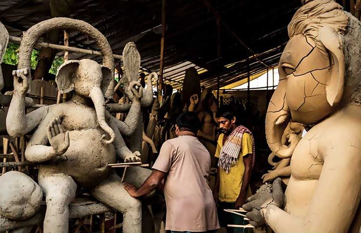 Artisans in a traditional workshop meticulously work on clay idols of Lord Ganesha, bringing the deity to life with skillful hands and centuries-old techniques.